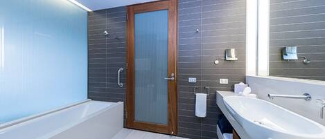 A modern bathroom with a bathtub, a large mirror, and a vanity with a sink.