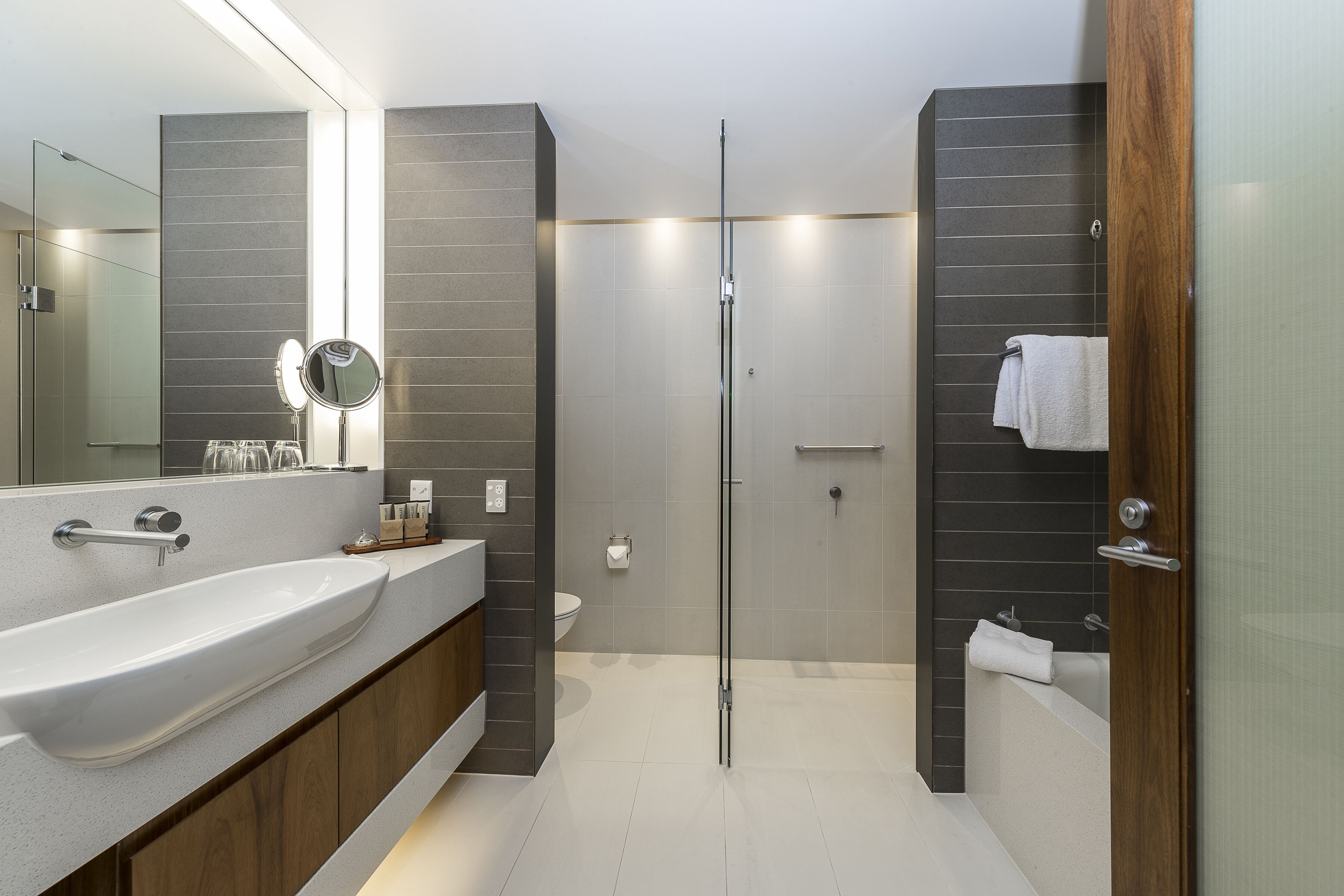 Un baño moderno con un lavamanos grande, un espejo y una ducha con cerramiento de vidrio.