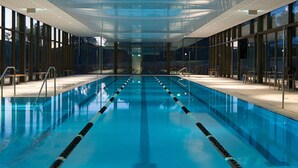 Une piscine intérieure dotée de couloirs bien délimités, de parois en verre et d’un design moderne.