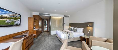 Une chambre d’hôtel moderne équipée d’un lit, d’un bureau, d’une chaise, d’une télévision et offrant une vue sur l’extérieur.