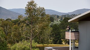 Un bâtiment moderne doté d’un balcon donnant sur un lac et des collines.
