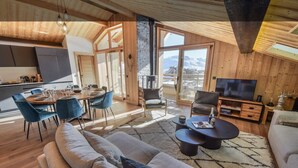 A modern interior with a dining area, sofa, TV, and a fireplace. - Prestigious ski-in/ski-out apartment with panoramic view (Huez)