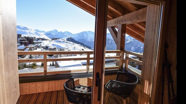A wooden balcony with a view of snow-covered mountains and a town below. - Prestigious ski-in/ski-out apartment with panoramic view (Huez)