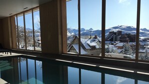 A swimming pool with a view of snow-covered buildings and mountains. - Prestigious ski-in/ski-out apartment with panoramic view (Huez)