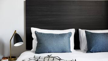 A neatly made bed with two pillows, a bedside lamp, and a small table with a candle.