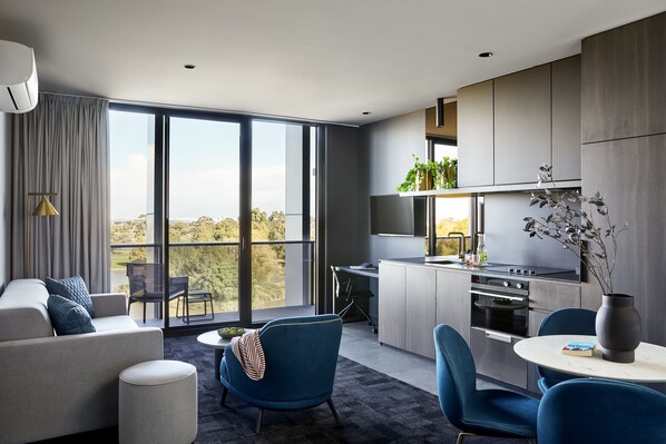 A modern apartment with a living area, kitchen, and large windows offering a city view. - Punthill Caroline Springs (Caroline Springs)