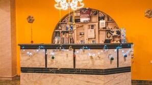 A reception desk with a marble top, surrounded by a curved shelving unit filled with books and decorative items. - Dahab Plaza Hotel (Dahab)