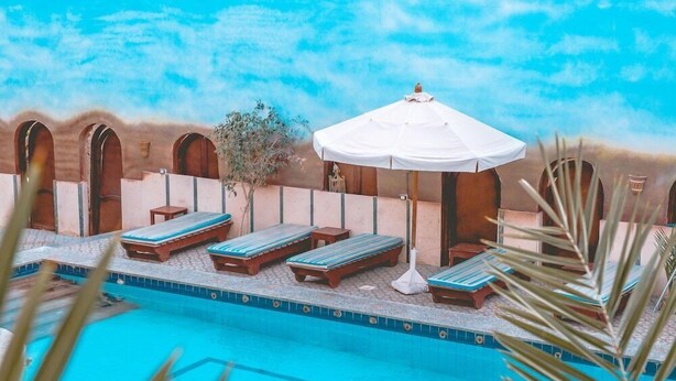 A pool area with lounge chairs and a white umbrella. - Dahab Plaza Hotel (Dahab)