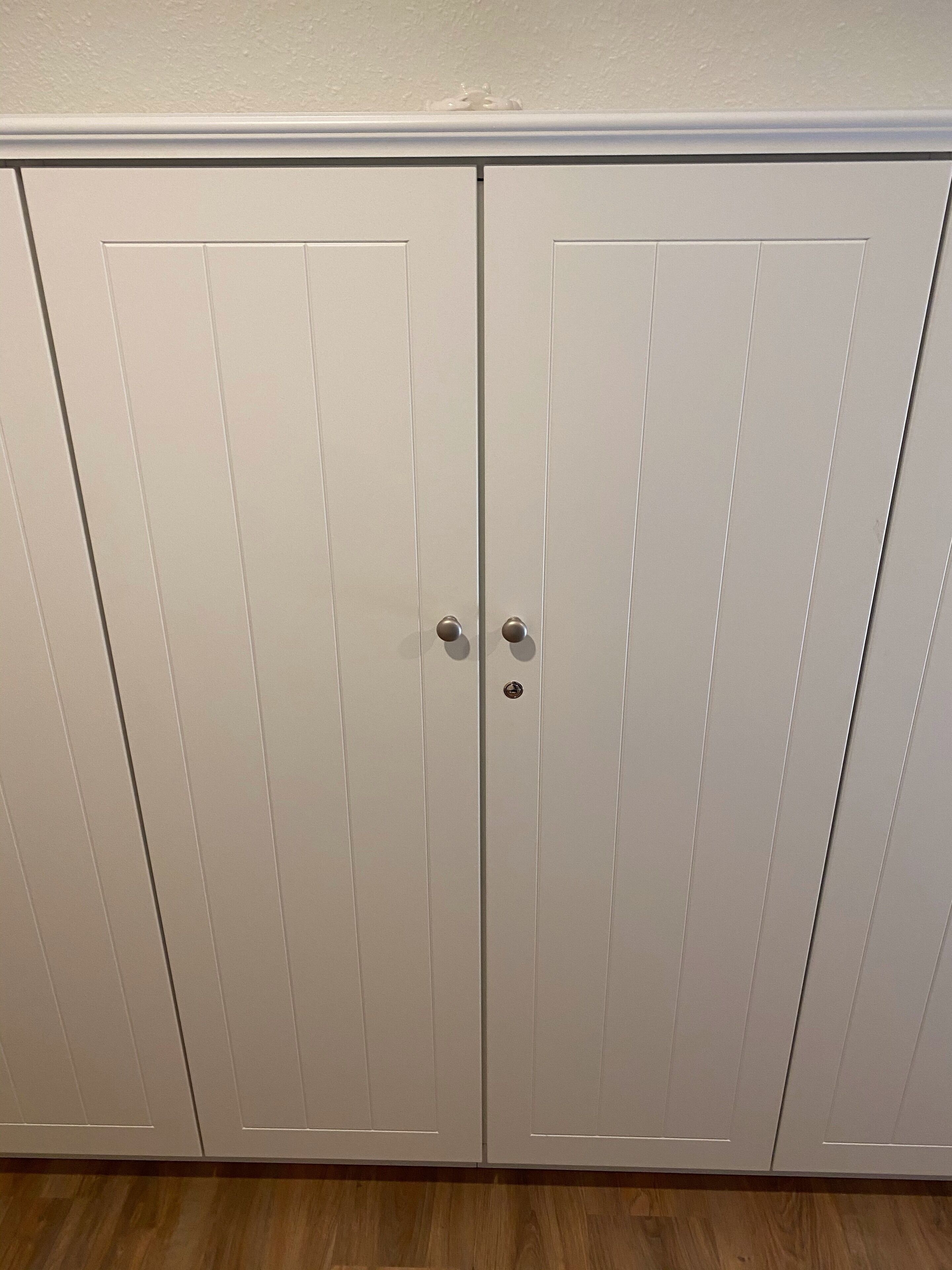 A white wardrobe with two doors and a small keyhole lock.