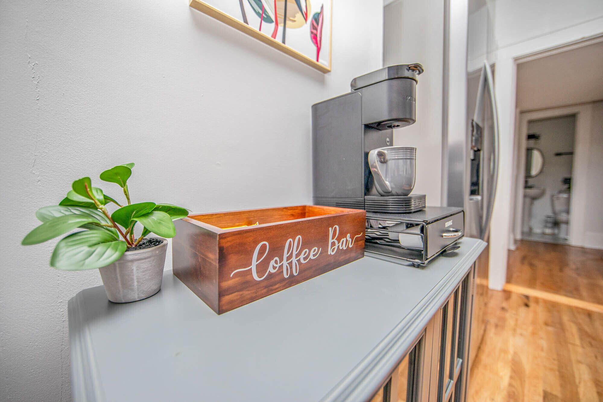 Ein Café mit einem Holzschild, einer Kaffeemaschine und einem Blumentopf auf einer weißen Theke.
