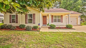 A single-story house with a front porch, a garage, and a well-maintained lawn. - The Strickland Stopover (Fayetteville)
