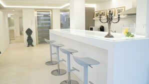 A modern kitchen with a white countertop, three bar stools, and a candelabra. - acquabianca plus (Catania)