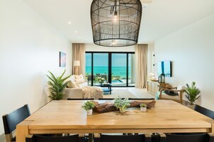 Un amplio salón con una gran mesa de madera, asientos cómodos y vistas al océano a través de grandes ventanales.