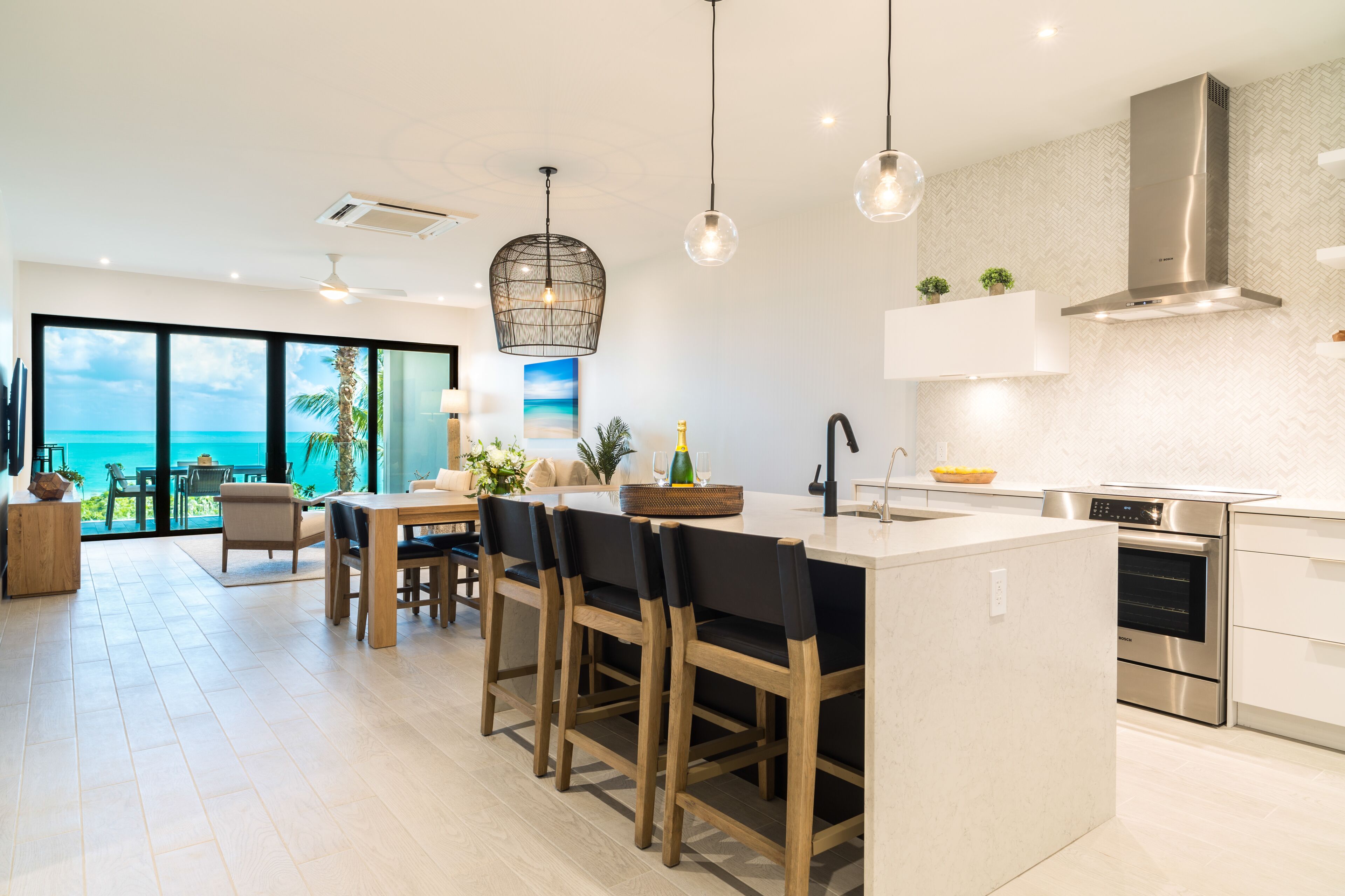 Una cocina moderna con una isla grande, electrodomésticos de acero inoxidable y vistas al océano.