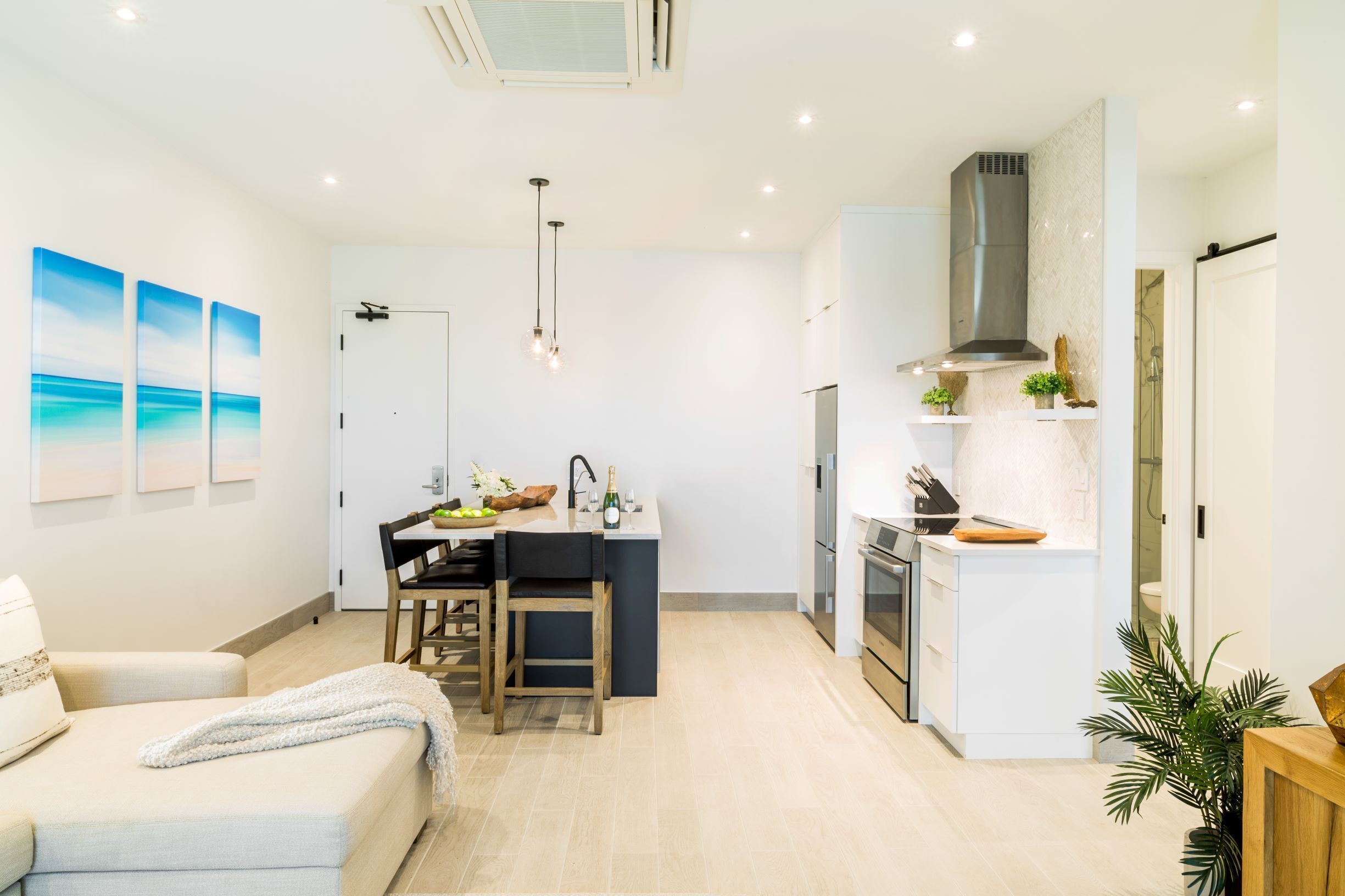 Una cocina moderna con una isla central, electrodomésticos integrados y un comedor con vistas al mar.