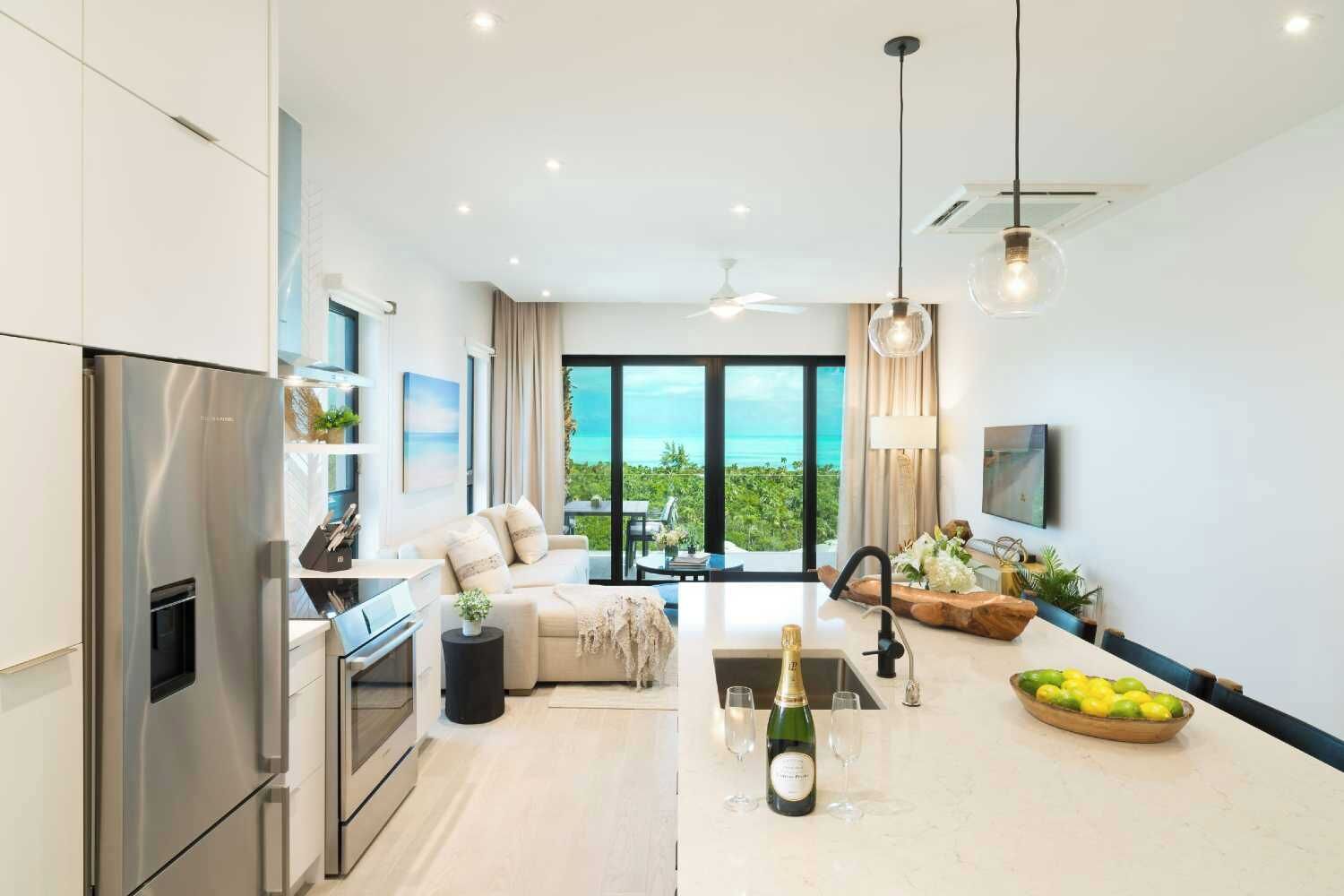 A modern kitchen with a built-in oven and a large island with a sink and wine glasses.