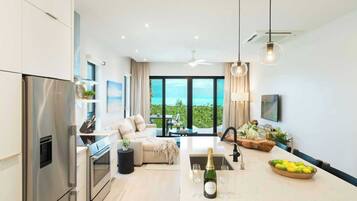 A modern kitchen with a built-in oven and a large island with a sink and wine glasses.