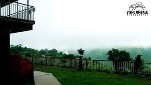 A view of a lush green landscape with a fence and a building in the foreground. - The Byke Sai Cottage, Mahabaleshwar (Satara)