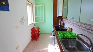 Una cocina con pared verde, ventana, fregadero y estufa.