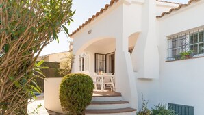 A white building with a tiled roof, a staircase leading to a covered patio, and a window with a metal grill. - Magnificent villa between sea and forest with private pool and free wifi. (L'Escala)