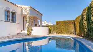 A swimming pool with a curved edge, a white building with arched windows, and a neatly trimmed hedge. - Magnificent villa between sea and forest with private pool and free wifi. (L'Escala)