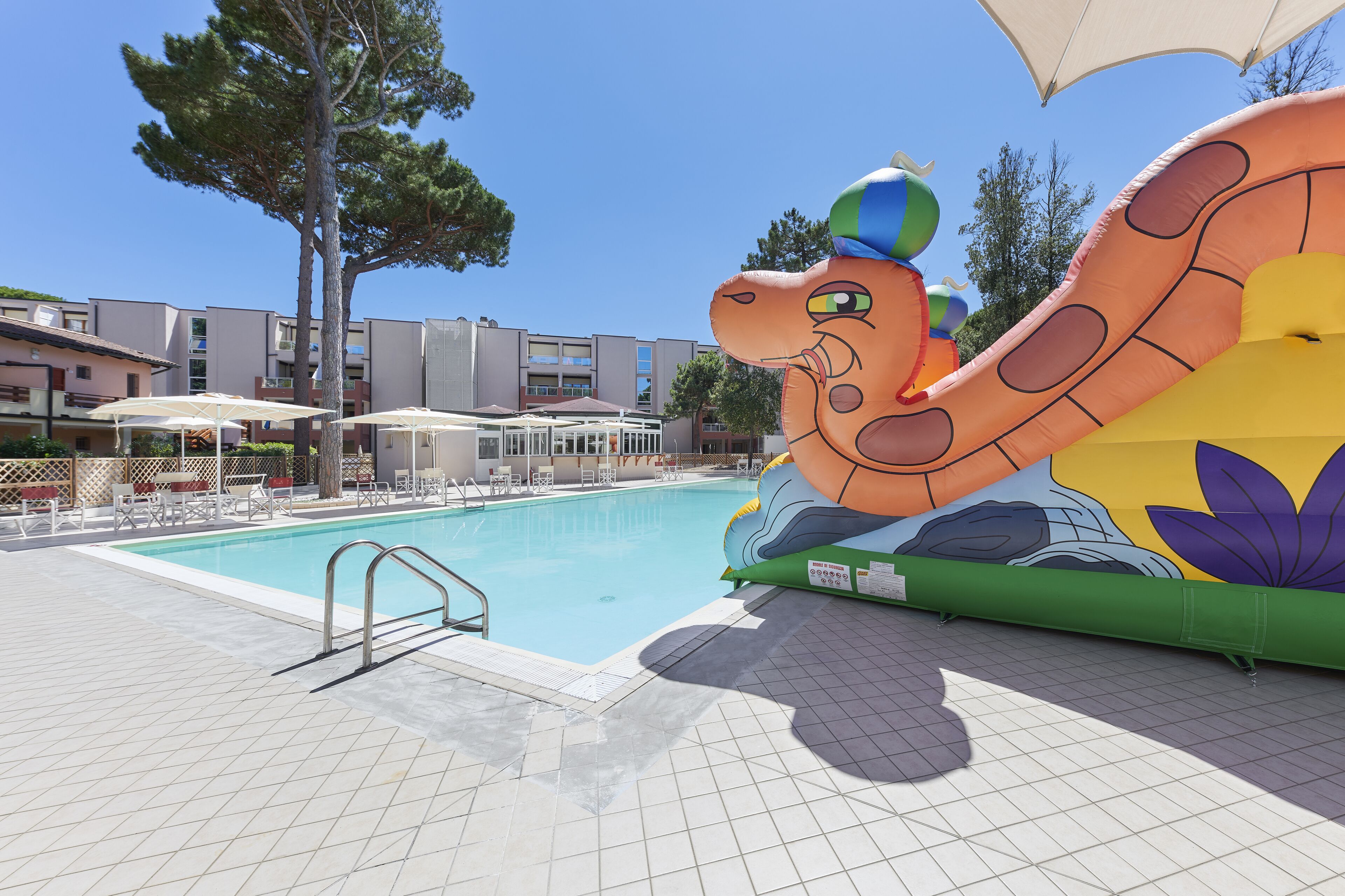 A swimming pool with a large inflatable octopus decoration, lounge chairs, and umbrellas.