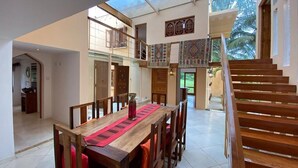 A spacious dining area with a wooden table and chairs, a staircase, and a view of the outdoors. - Villa 47 Vipingo Ridge (Vipingo)