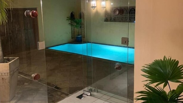 A glass-enclosed swimming pool with a tiled floor, surrounded by walls with a light-colored finish and a wooden ceiling. - Villa 47 Vipingo Ridge (Vipingo)