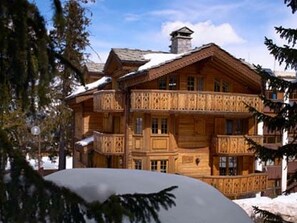 A large wooden chalet with multiple balconies and a snow-covered roof.