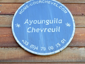 Een rond bord met de tekst 'Ayounguila Chevrolet' en een websiteadres 'HOME-COURCHEVEL.COM'.