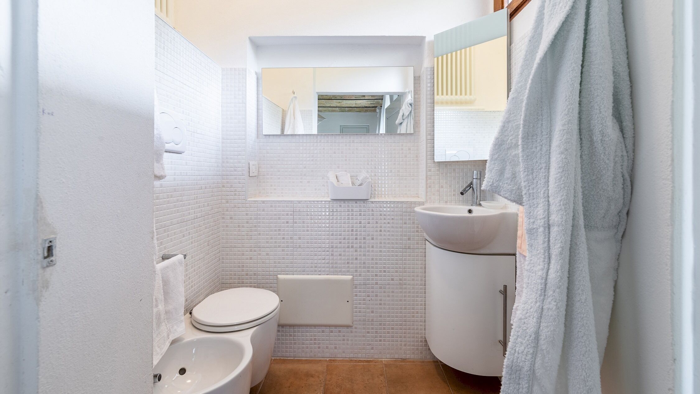 Une petite salle de bain comprenant des toilettes, un lavabo et un miroir.
