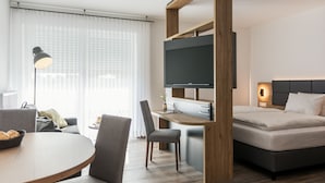 Een moderne hotelkamer met een bed, bureau en televisie.