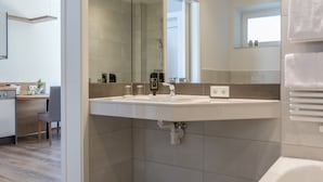 Een moderne badkamer met een grote spiegel, een wastafel en een douche.