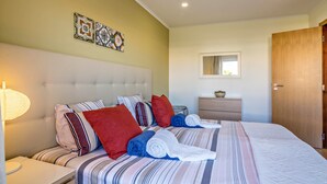 Une chambre d’hôtel comprenant un lit, une table de chevet, une lampe, une commode, un miroir et une porte.