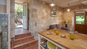 Une cuisine avec une table en bois, un escalier et un mur en pierre.