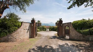 A gated entrance with stone walls and metal gates, leading to a gravel path. - ❤️Luxury Villa with pool. NEW❤️ (pietrasanta)