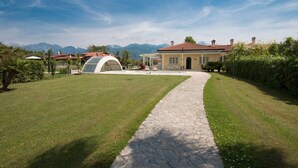 A house with a stone pathway leading to a covered area, surrounded by well-maintained grass and a clear sky. - ❤️Luxury Villa with pool. NEW❤️ (pietrasanta)