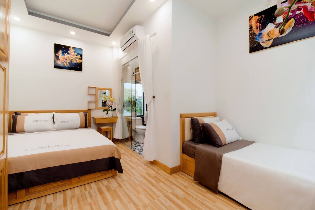 A hotel room with two beds, a small desk, and a window with a view.