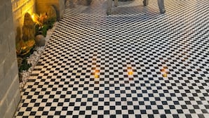 A courtyard with a checkered floor, a mural of a canal scene, a table with chairs, and a stone wall. - Hoian Royal Villa (Da Nang)