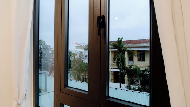 A window with a view of buildings and a palm tree outside. - Hoian Royal Villa (Da Nang)