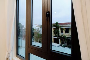Janela com vista para edifícios e uma palmeira lá fora.