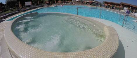 Relax by the pool with a hot tub and lounge chairs on a spacious deck.