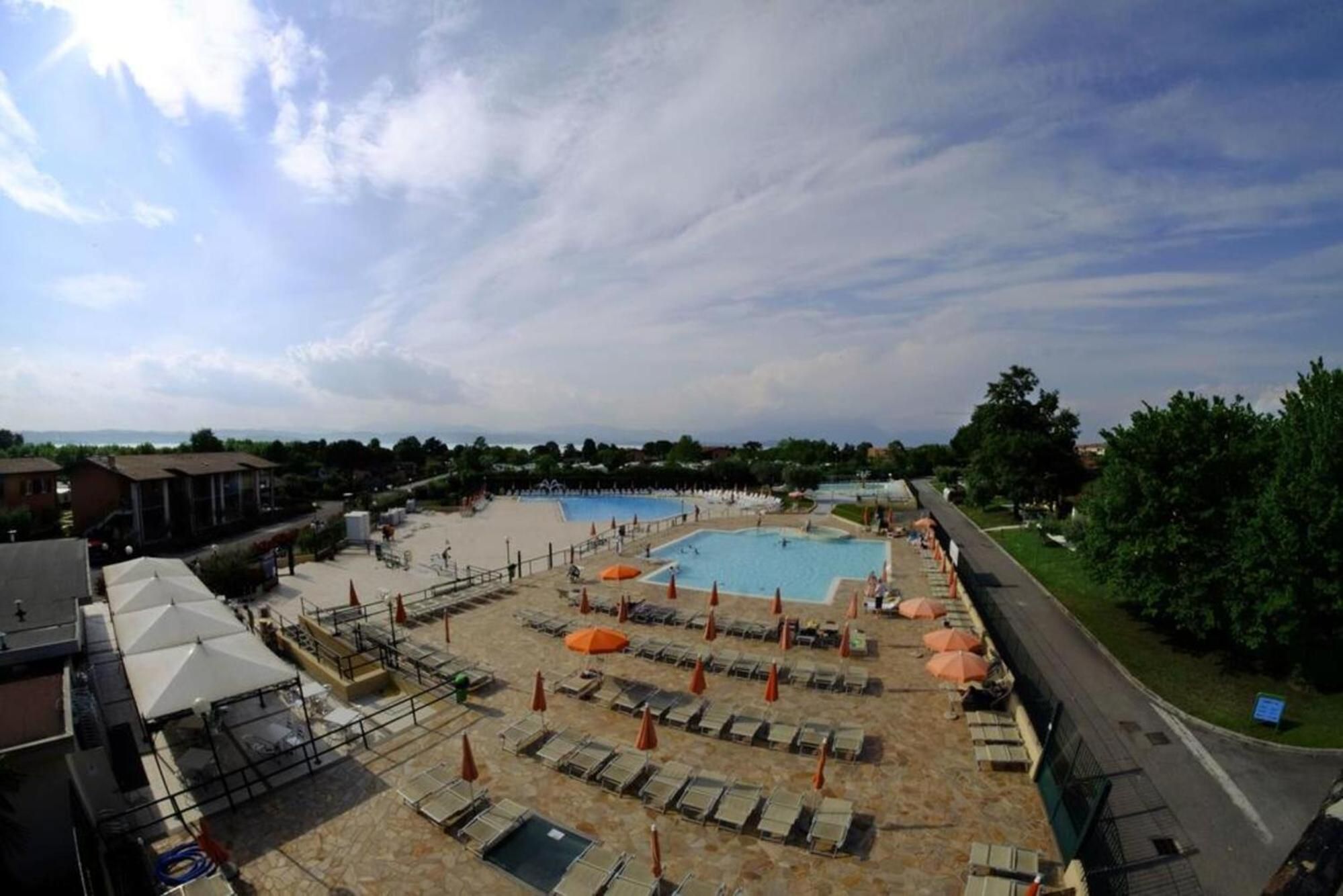 Zona de piscina amb diverses piscines, gandules i paraigües.