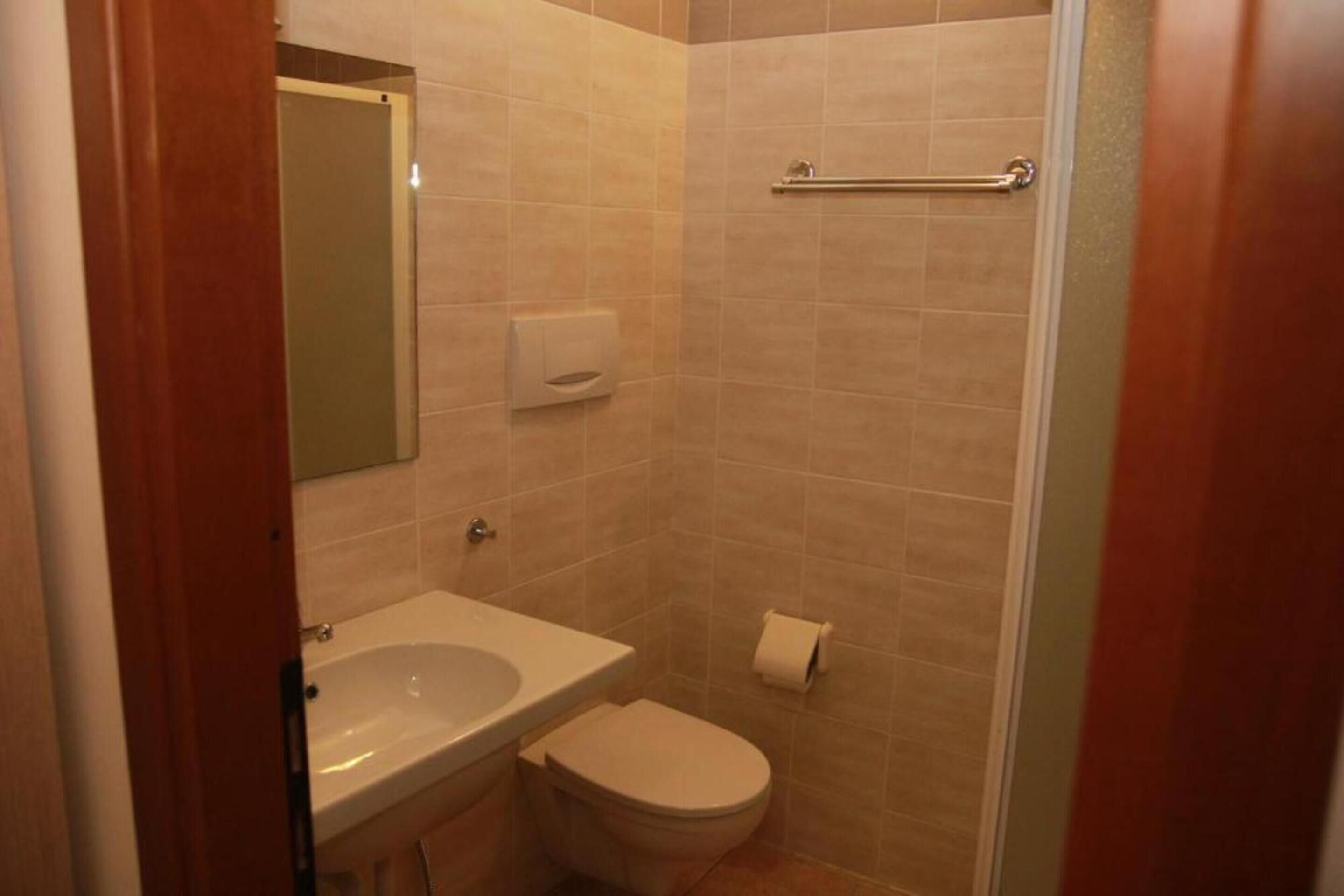 Et lille badeværelse med håndvask, toilet og bruseområde.