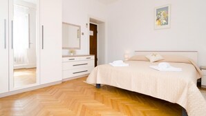 Een slaapkamer met een bed, een kledingkast, een dressoir en een schilderij aan de muur.