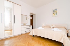 A bedroom with a bed, a wardrobe, a dresser, and a painting on the wall. - Holiday Home Patricija (Dubrovnik)