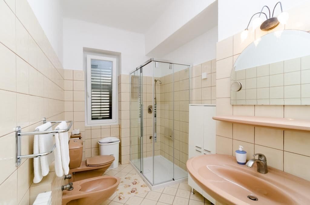 A modern bathroom with a glass-enclosed shower, a sink, and a toilet.