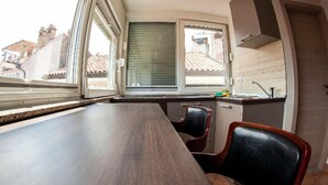Une cuisine avec une fenêtre, un évier et un coin repas avec des chaises.
