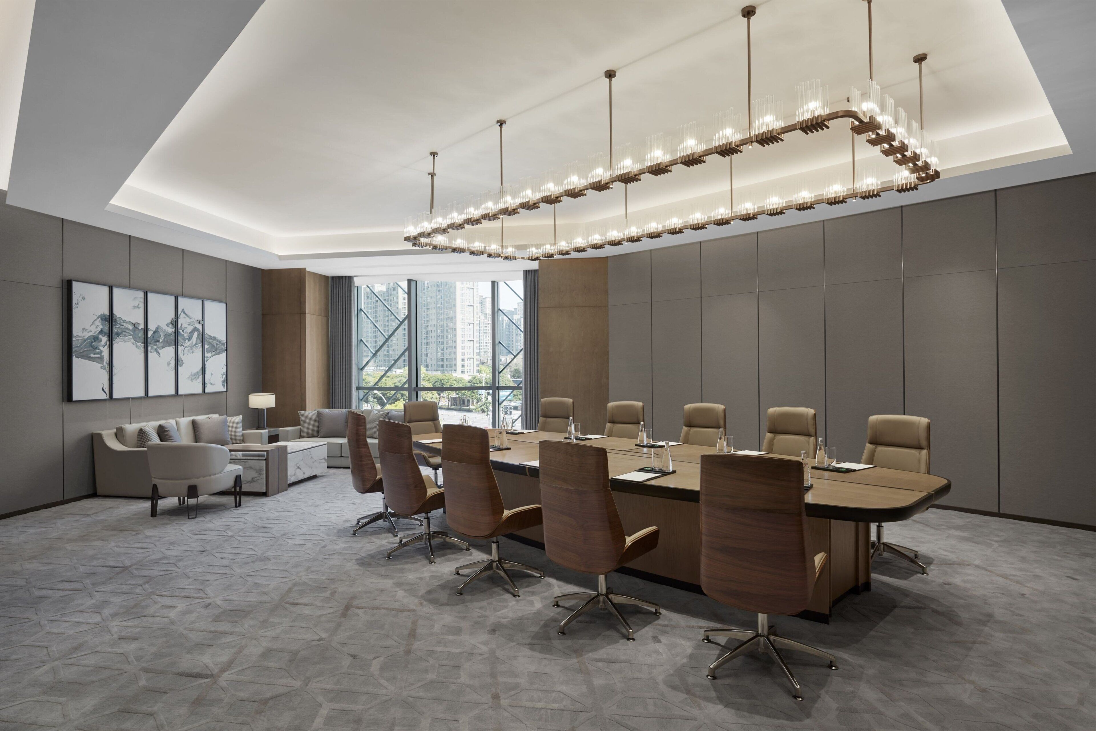 Une salle de conférence moderne, dotée d’une longue table, de chaises confortables et d’un lustre original.