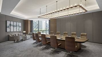 A modern conference room with a long table, comfortable chairs, and a unique chandelier.